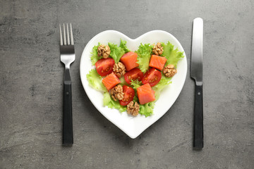 Plate with salad on grey background, flat lay. Heart-healthy diet