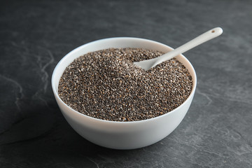 Bowl and spoon with chia seeds on grey background