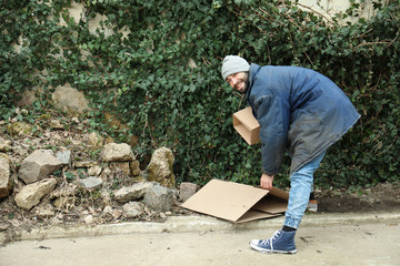 Poor homeless man with cardboard on street