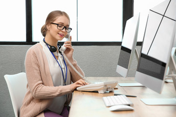 Technical support operator talking on telephone at table in office