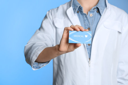 Doctor holding business card on color background, closeup with space for text. Dental medical service