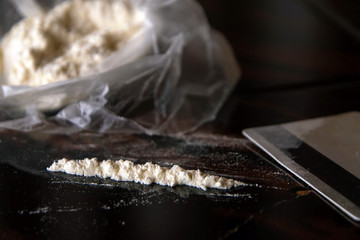 strip of cocaine on a background of packing with a drug and a plastic card