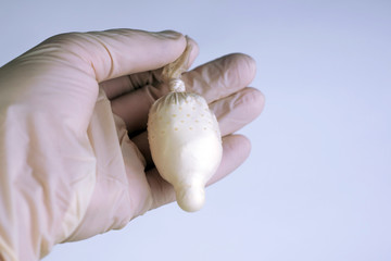 detection of cocaine and heroin: a laboratory medical officer holds in his hand a transport container made of a condom with a sample of a narcotic powder for analysis, toning
