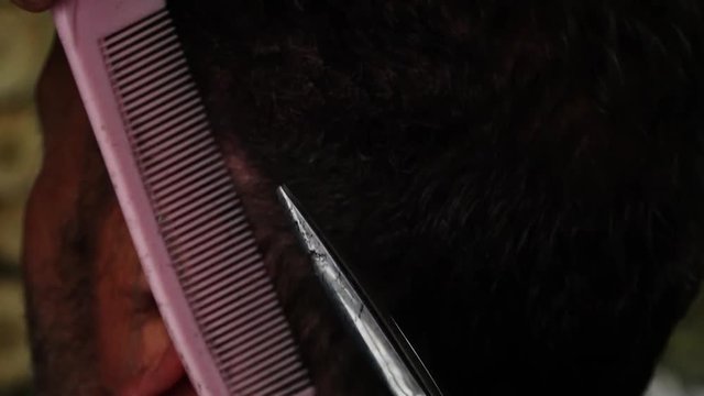 A hand held, extreme close up shot of a man getting a haircut by a professional hairdresser. 