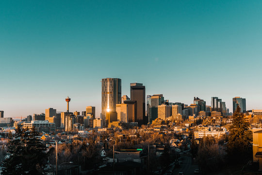Calgary skyline in the early morning with rays from rising sun reflecting off glass buildings.