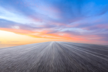 Motion blurred asphalt road ground and sky sunset clouds