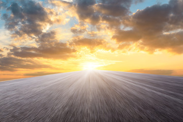 Motion blurred asphalt road ground and sky sunset clouds