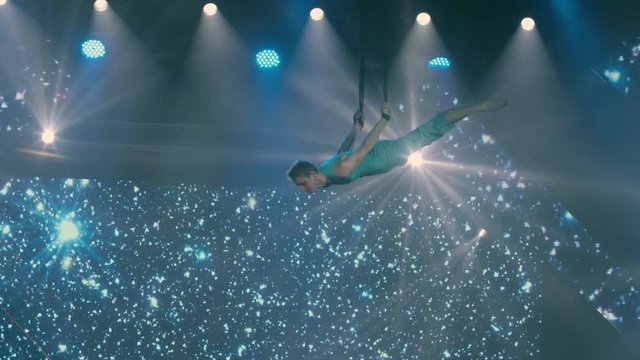 Vladivostok, Primorsky Krai / Russia - 04 13 2019: Slow-motion video of a gymnast rotating on the ropes in the light of searchlights