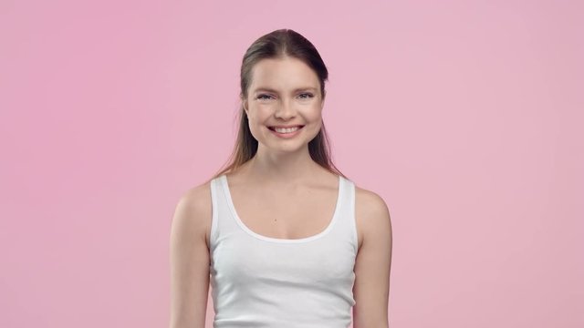 Woman throws out razor and smiling on light pink background