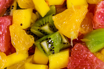 Background of the chopped exotic fruits. Mango, oranges, grapefruit and kiwi