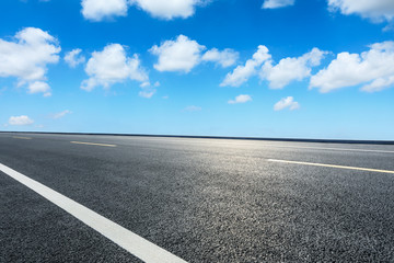 Fototapeta premium Empty asphalt road ground and blue sky with white clouds scene