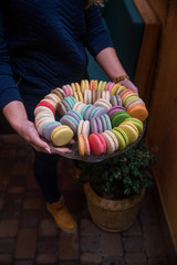 Girl holding a big plate with macaroons, a big variety of macaroons. Sweets photography.