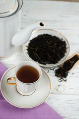 Teapot and cups on the wooden white table. Aromatic black tea. Concept of tea ceremony, break and having rest.