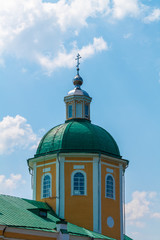 Obraz premium Yellow Orthodox Christian church with a green dome in summer against a blue sky with white clouds.