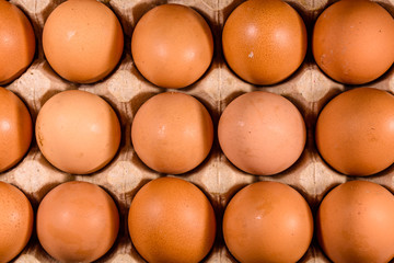 Pile of the hen eggs in paper tray on wooden table. Top view