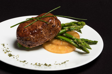 carne con esparragos y piña en plato blanco y fondo negro