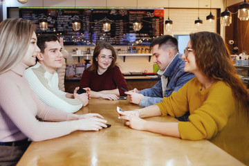 Five young handsome students sitting in a cafe.