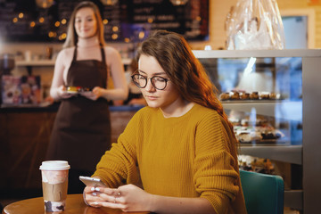 Young pretty woman and waitress in cafe.