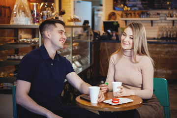 Two cute young students - boy and girl, sit in a cafe.