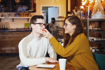 Two cute young men and a girl in a cafe.
