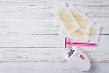 Epilator, razor and wax strips on white background