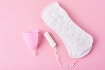Sanitary pad, menstrual cup and tampon on a pink background