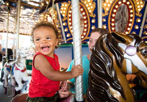 Cute mixed race little boy enjoying a ride on a fun carnival carousel. A happy boy Smiling and having fun riding a carousel ride at the summer carnival