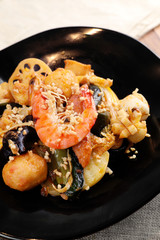 Fried fresh shrimp and black fungus in a dark ceramic dish