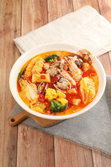 Spicy seafood include shrimp and flower clams in a white ceramic dish