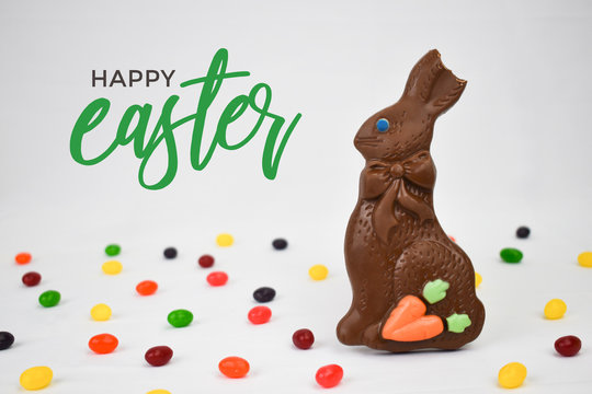 Chocolate Easter Bunny, Jelly Beans Candy and Happy Easter Calligraphy Text on White Background, Copy Space, Horizontal