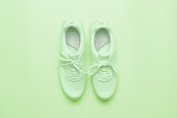 Pastel green sneakers on on the background of gently green.  Trendy athletics and sport minimal  concept. Fancy composition is made in one candy color. Flat lay, top view. 