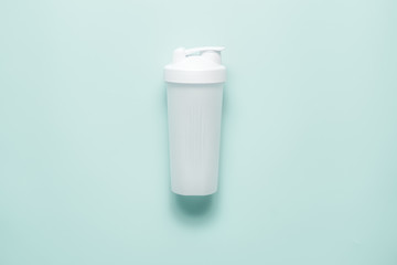 White plastic sports shaker on pastel turquoise background.  Trendy athletics and sport minimal  concept. Female fitness.Flat lay, top view. 