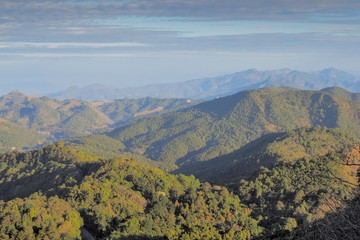 Mountain view morning on top of Doi Ang Khang above many hills and green forest cover with soft mist and blue sky background, Doi Angkhang, Chiang Mai, northern of Thailand.