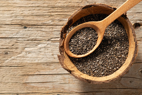 chia seeds in dishes on wooden background, place under the text, view from above