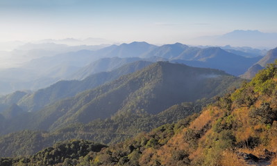 Fototapeta na wymiar Mountain view morning on top of Doi Ang Khang above many hills and green forest cover with soft mist and blue sky background, Doi Angkhang, Chiang Mai, northern of Thailand.