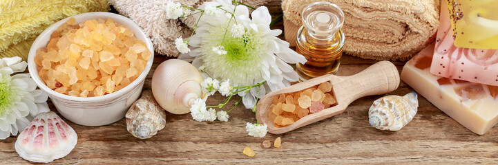 Soft towels, sea salt and shells on wooden background. Spa concept