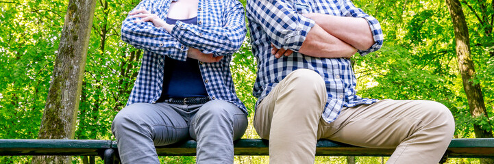 Angry couple sitting on the bench in beautiful summer park.