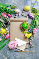 Colorful flowers and painted Easter eggs on grey, stone background