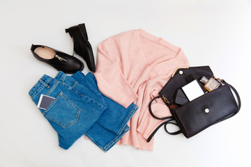 Women's fashion clothing and accessories. Female youth collage on white background top view. A flat lay-out in feminine style looks with a warm sweater, jeans, shoes. Top view. 