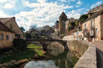 Obraz premium View of the ancient city of Semur-en-osua. There is a quay, a stone bridge, walls and towers of the castle. On both sides of the river are old houses. France. Burgundy.