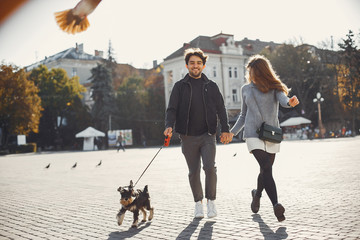 Cute couple in a spring city. Lady with long hair. Man in a black jacket. Two people with a dog