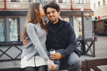 Fototapeta premium Cute couple in a spring city. Lady with long hair. Man in a black jacket. Two people with a coffee