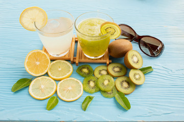 glass of lemon juice white lime and kiwi juice on blue wood background