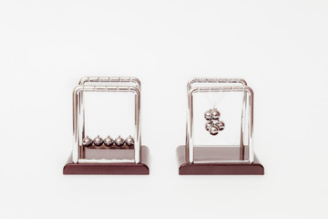Two metal Newton cradle placed on white background as representation of momentum concept and balance disorders