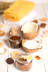 Fototapeta na wymiar Coconut, spa products, coffee scrub and seashells on white background