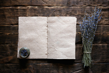 Dried lavender flower branch and a blank aromatherapy recipe book mock up on a wooden table...