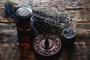 Dried lavender flower branches and lavender essential oil bottles on a wooden table background....