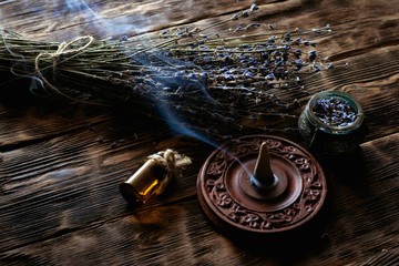Dried lavender flower branches and lavender essential oil bottles on a wooden table background....