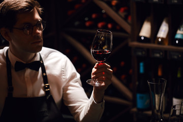 Cavist at store, sommelier at restaurant, critic. Wine Degustation. tasting experience in the club, man holding a glass of delicious wine.