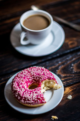 Bite a Pink donut with white sprinkle
